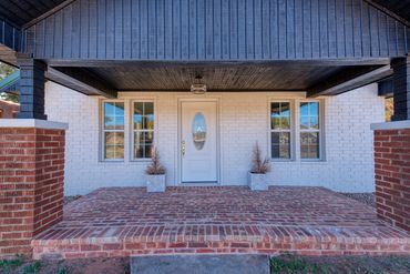 Remodeled Elk City brick home, painted white exterior, covered front porch, glass oval front door