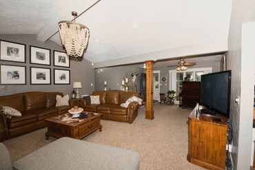 Elk City real estate photography—spacious living room with leather sofas, chandelier, piano