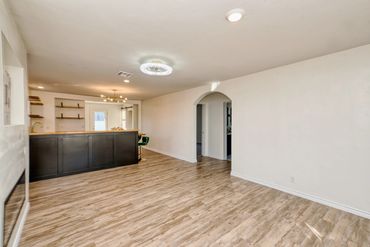 Open concept living room in Elk City home with wood look flooring, breakfast bar, modern lighting