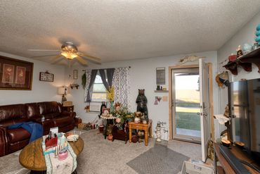 Eakly, OK living room with open front door, leather sofa, window AC—Western Oklahoma rural home