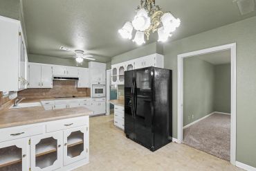 Kitchen with white cabinets and black refrigerator - real estate photo, Sayre, OK
