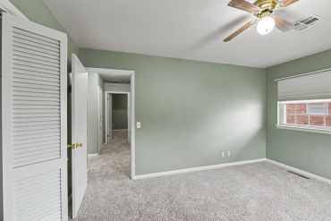 Empty bedroom with ceiling fan and hallway view - real estate photo, Sayre, OK
