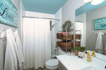 Western Oklahoma real estate photography—guest bathroom with white shower, vanity, wicker storage