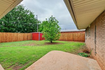 Fenced backyard with lawn and young tree - real estate photo, Sayre, OK