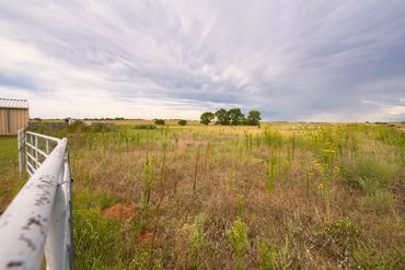 Photo of property included in a listing for a Sayre, OK home. Includes pipe fence, dramatic sky