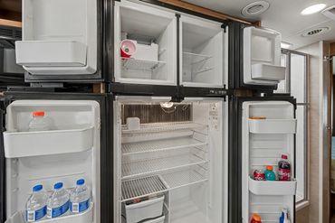 Well-lit professional photograph showcasing the open refrigerator/freezer of a recreational vehicle