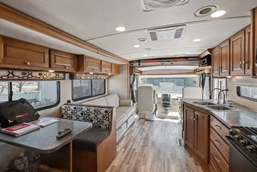 View toward the front of an RV. Dining area with remotes and manuals visible.