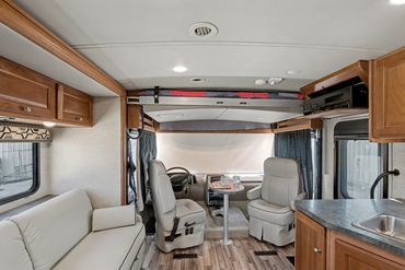 Photo featuring an RV's captain chairs and removable table, with sofa seating visible on the left