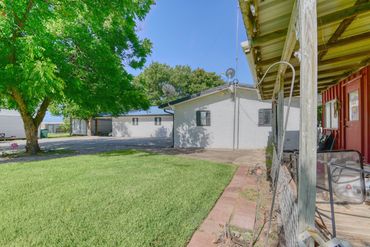 Photograph showing the porch of an outbuilding and the front yard of a home in north Texas