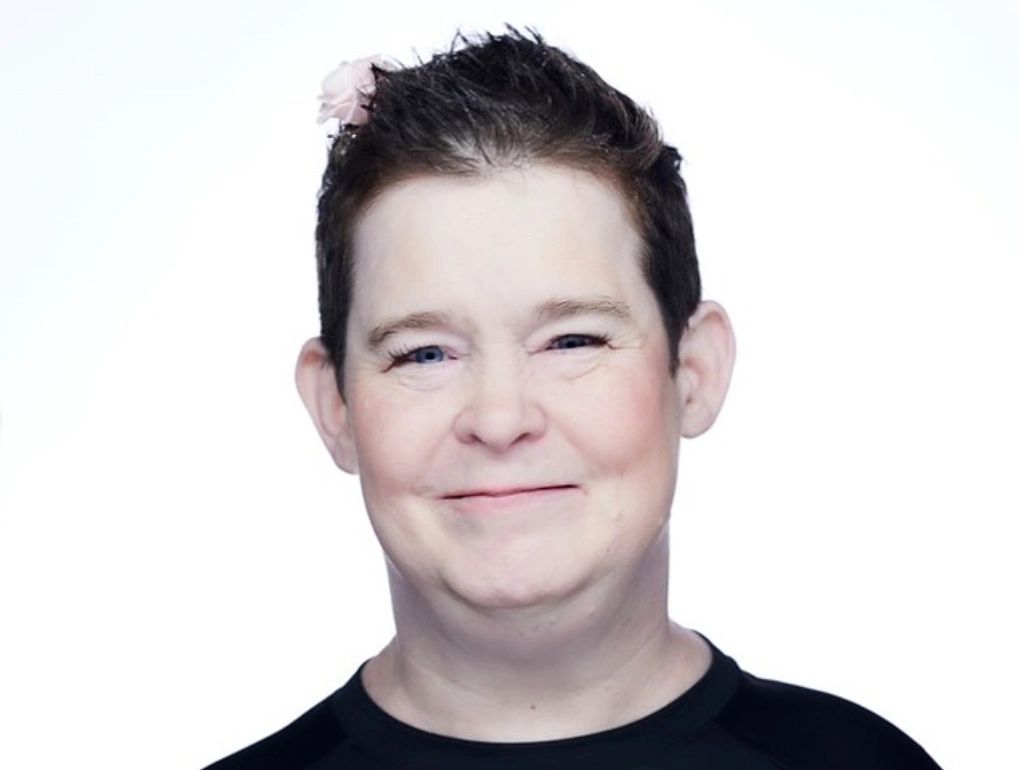 Kathleen's head & shoulders. Wearing a black shirt. She has very short brown hair and blue eyes.