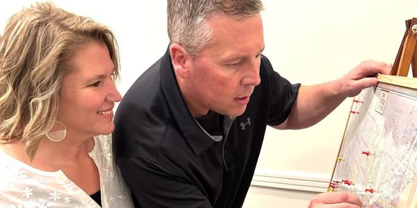 Couple pins locations on a map, holding a marriage reboot certificate.