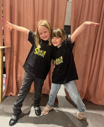 Two young girls joyfully posing in matching Sing Star t-shirts.