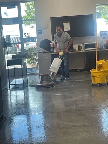Man cleaning floor with a polishing machine indoors.