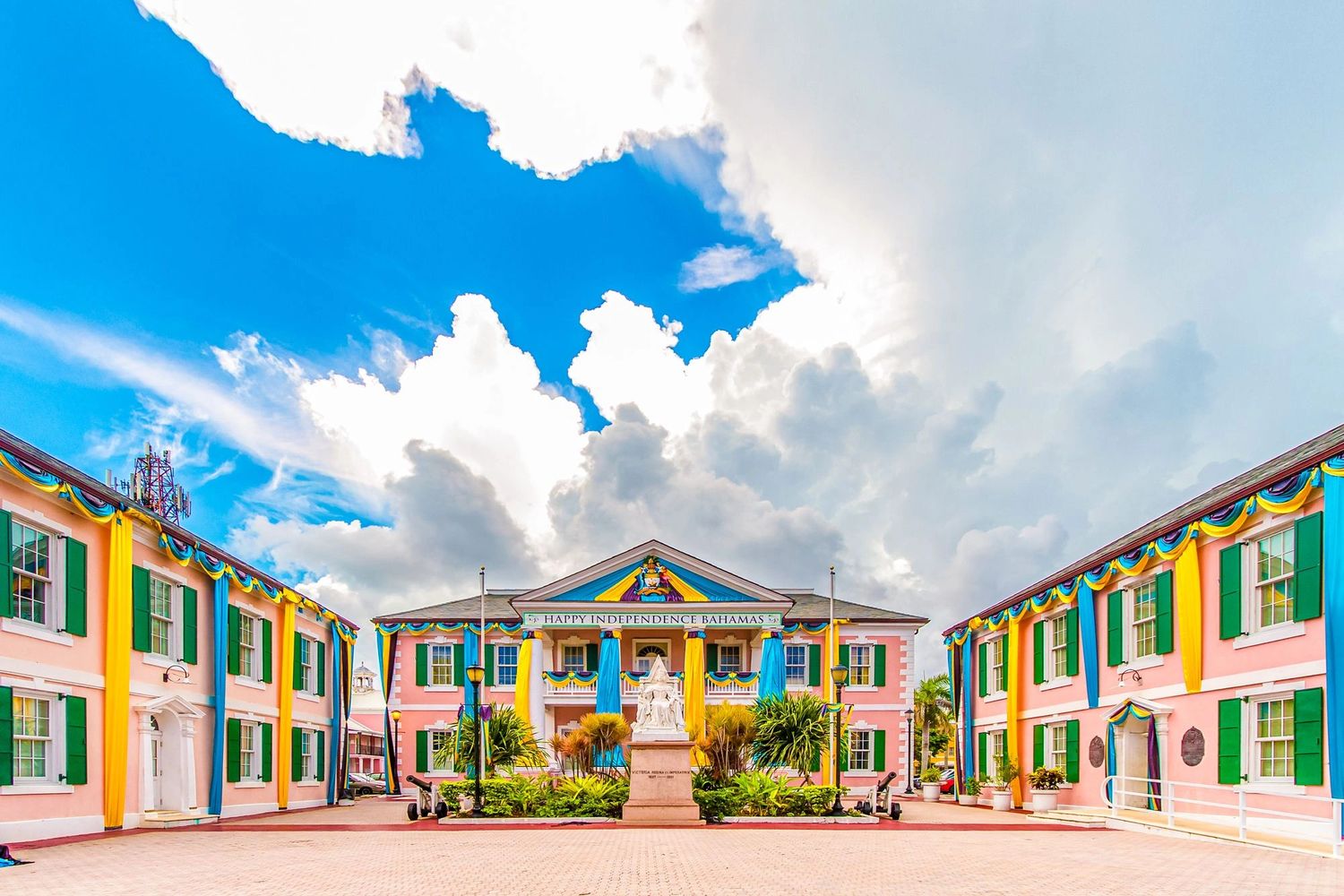 Colorful colonial buildings decorated for Bahamian Independence Day under a bright sky.