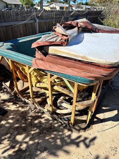 Damaged hot tub with missing exterior panels and exposed insulation.