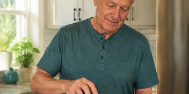 Senior man spreading peanut butter on toast in kitchen.