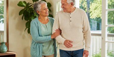 Elderly couple walking indoors, smiling at each other.