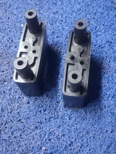 Two black plastic components on a blue textured surface.