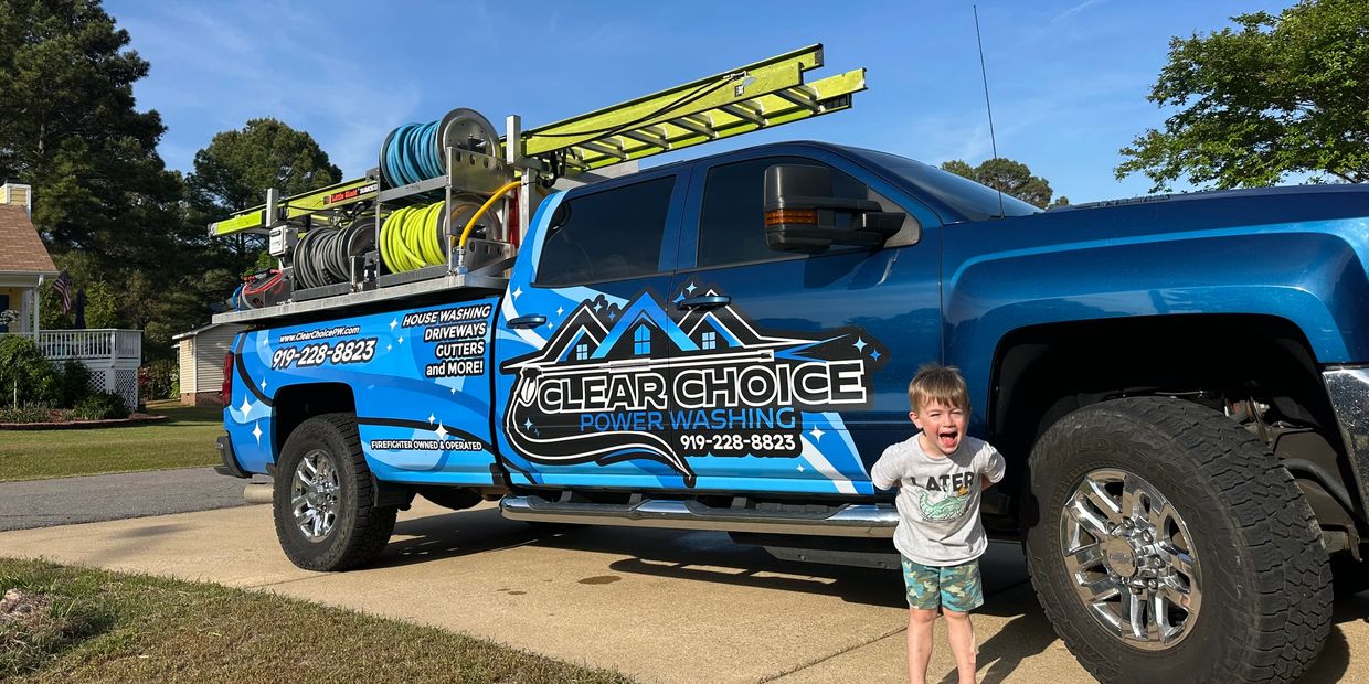 Child standing next to a Clear Choice power washing truck.