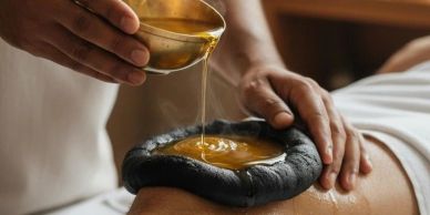 Therapeutic oil is poured over a herbal compress during a massage session.