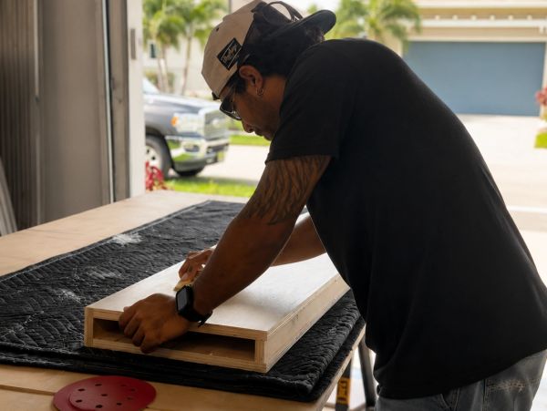 Man assembling a wooden box on a workbench outdoors.