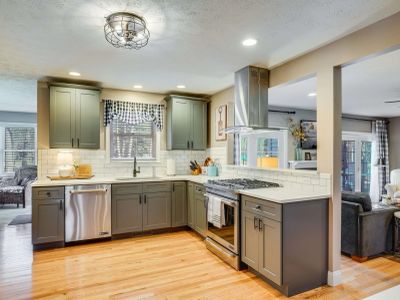 Modern kitchen with green cabinets and stainless steel appliances.