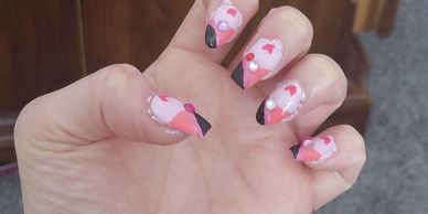 Hand with flamingo-themed nail art featuring pink and black accents.