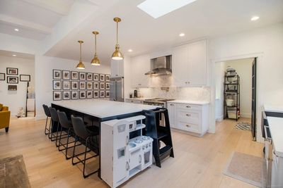 Modern white kitchen with large island and black chairs.