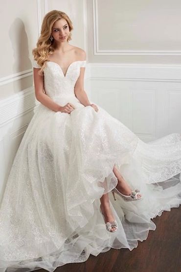 Bridal Dresses, Wedding Gowns: Eddy K, House of Wu, Mori Lee, Exclusive Moonlight, Private Label Designers. Unforgettable Bridal Boutique bride living out her bride journey. This is a Bride in a beautiful off-shoulder white wedding gown sitting gracefully.