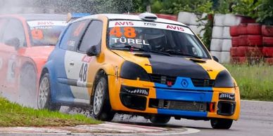 Race cars competing on a wet track, turning a corner closely.