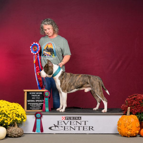 Woman with a dog and award ribbons at Purina Event Center.