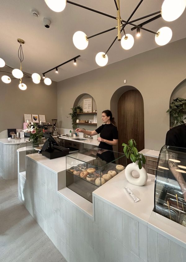 Modern cafe interior with barista and donuts on display.