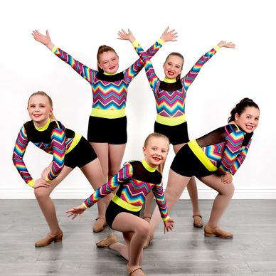 Young girls in colorful dance costumes posing.