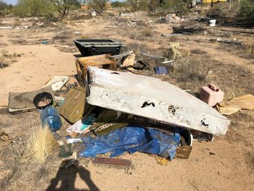 Trash and debris scattered in a dry, desert-like area.