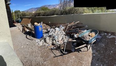 Construction debris and materials scattered in a backyard under clear blue sky.