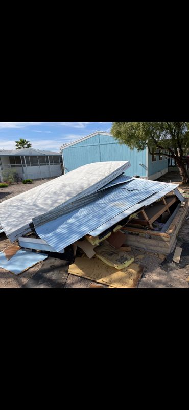 Collapsed shed roof with metal panels and insulation on the ground.