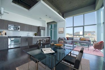 Modern open-concept living space with kitchen, dining, and lounge area with large windows.