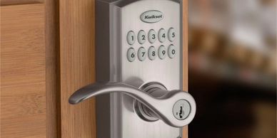 Modern Kwikset keypad door lock on wooden door.
