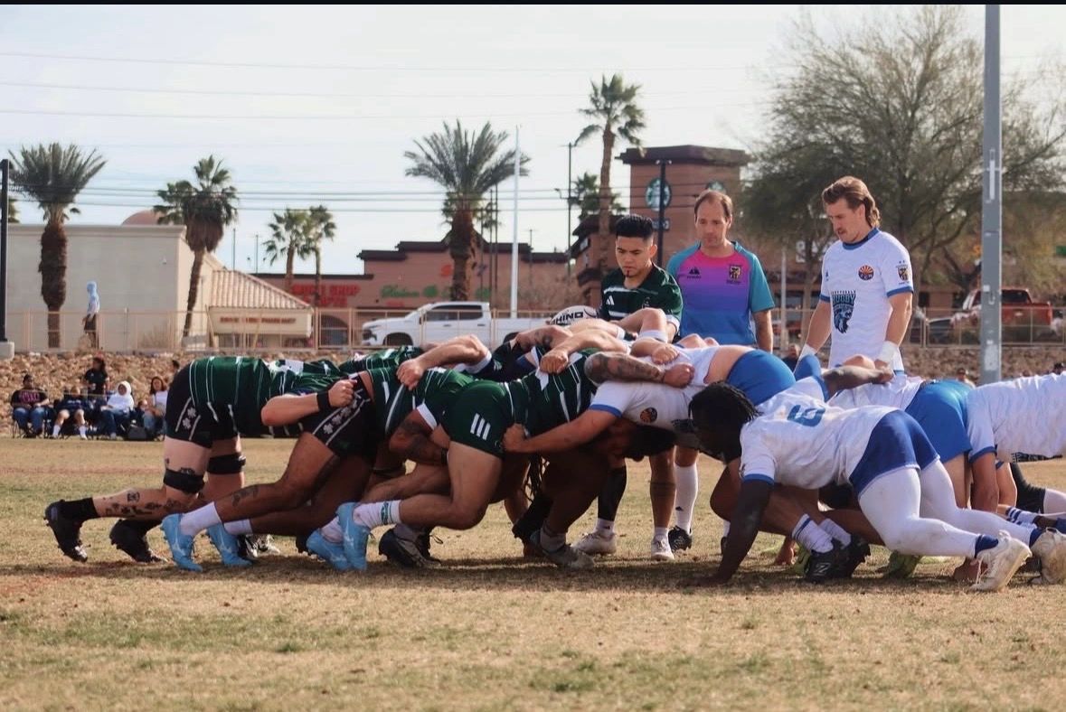 Two rugby teams engaged in a scrum on a sunny field with referees observing.