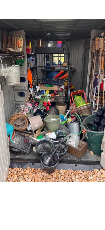 Cluttered garden shed filled with pots, tools, and gardening supplies.