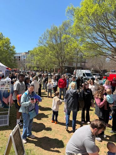 Crowd enjoying a sunny day at an outdoor market with handmade crafts and families.