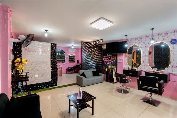 Bright pink beauty salon with modern styling chairs and mirrors.