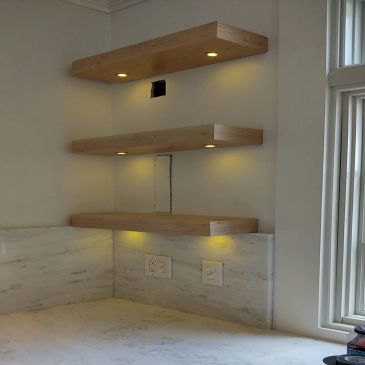 Floating wooden shelves with built-in lighting in a kitchen corner.
