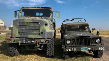 Two military vehicles, one large and one small, parked side by side outdoors.