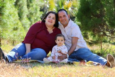A happy family sitting outdoors on a blanket.