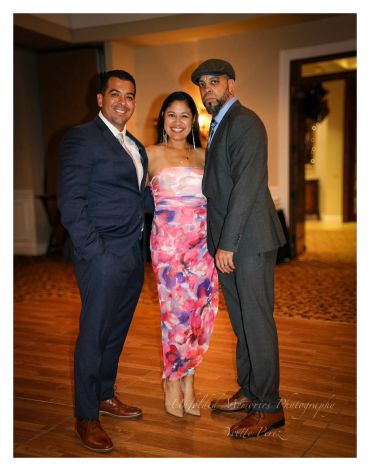 Three people posing together at an indoor event.