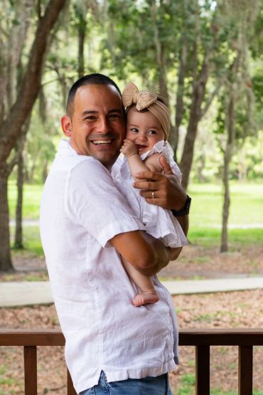 Happy man holding a smiling baby outdoors.