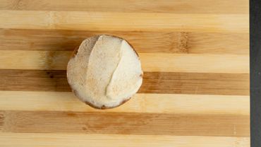 Frosted cupcake on a wooden cutting board.