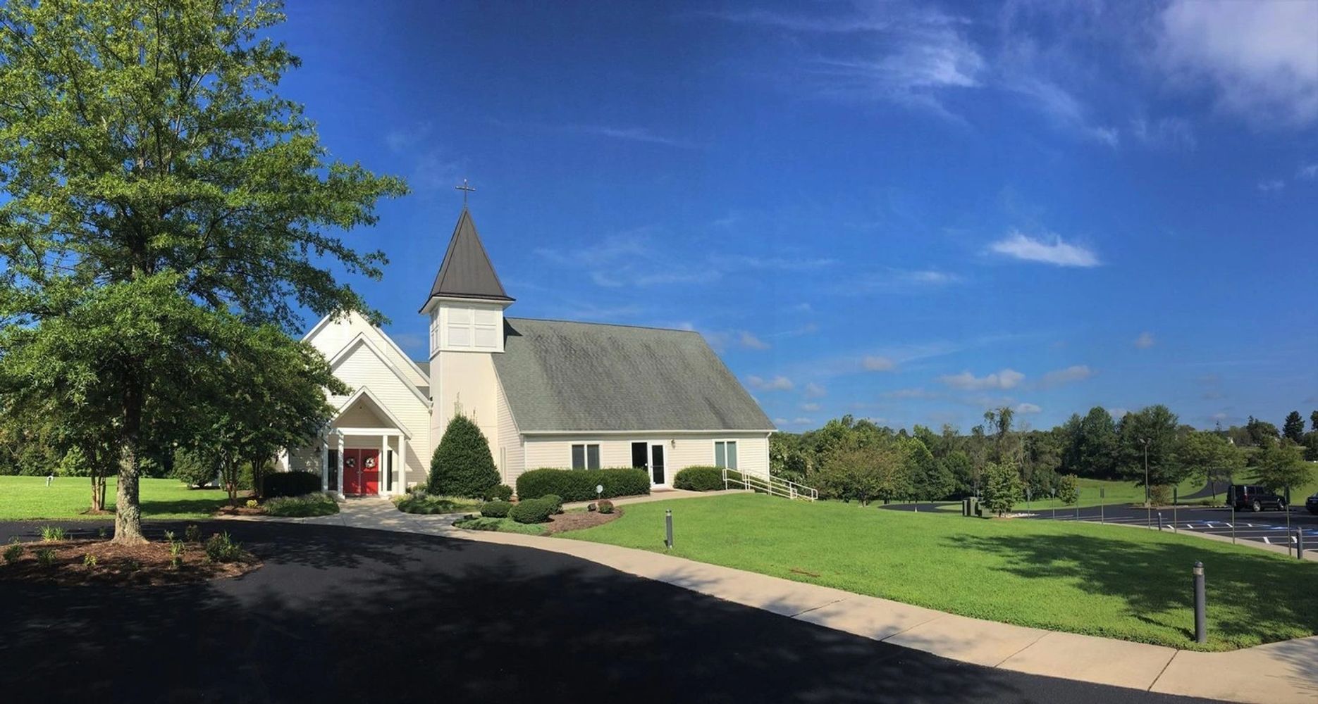 A white church with a steeple under a bright blue sky.