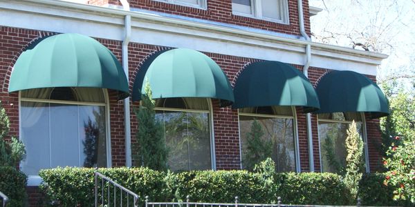 Forest green Sunbrella canvas aluminum frame dome awnings on red brick house